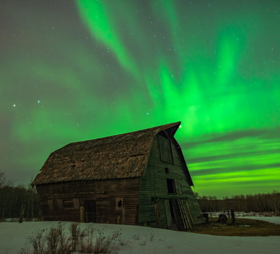 Aurora Borealis fires in the Saskatchewan night sky over an abandoned barn