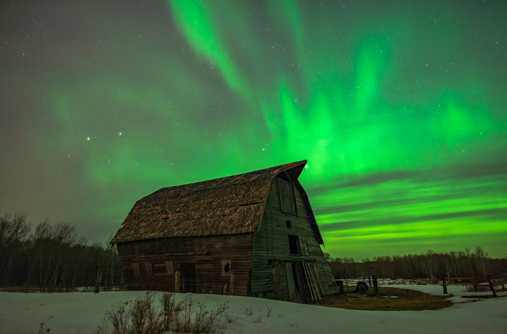 Aurora Borealis fires in the Saskatchewan night sky over an abandoned barn