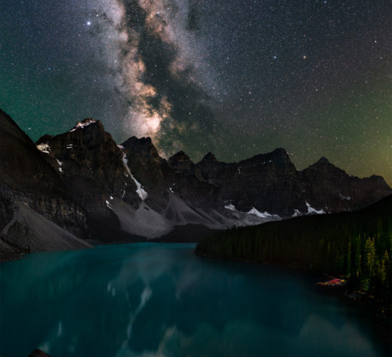 A night photograph of Moraine Lake, Alberta in Banff National Park. the milky way reflects in the pristine blue waters