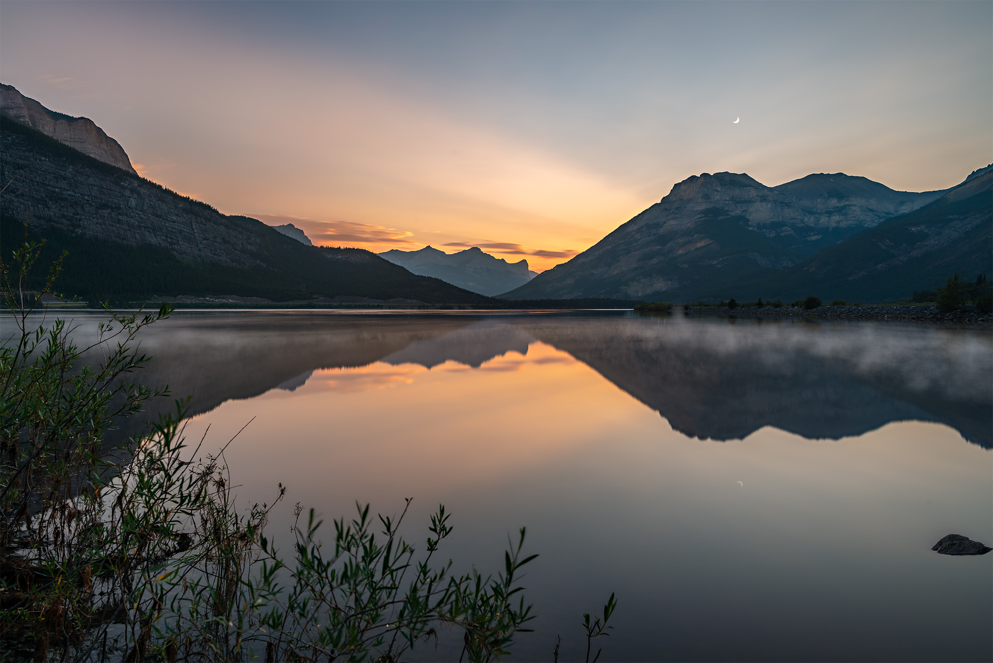 Sunset at lac Des arcs Alberta. A perfect reflection of the mountain range on a calm lake