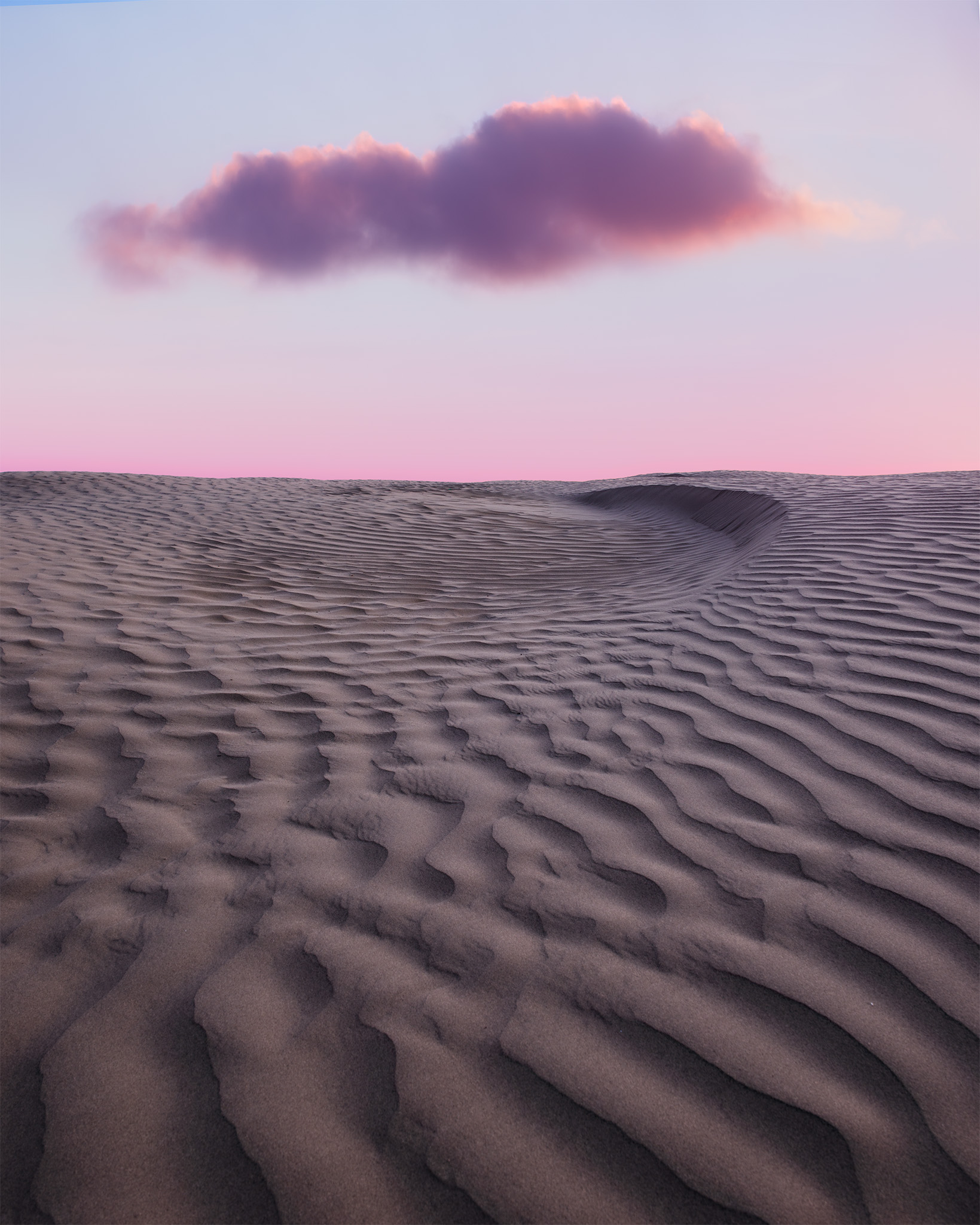 A landscape photograph of the Great Sandhills of Saskatchewan. Sand dunes and a cloud