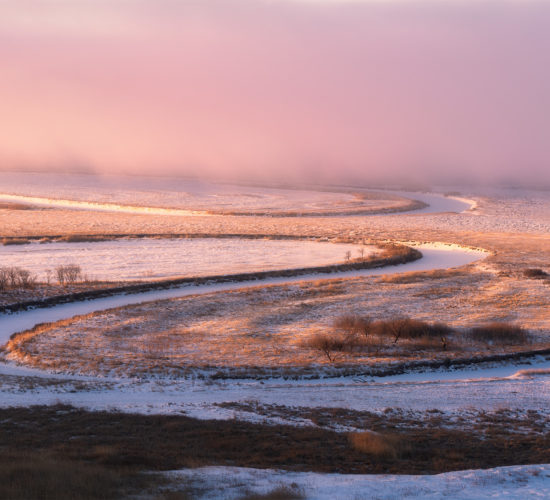 Light hits the Saskatchewan landscape as a frozen river winds through the scene
