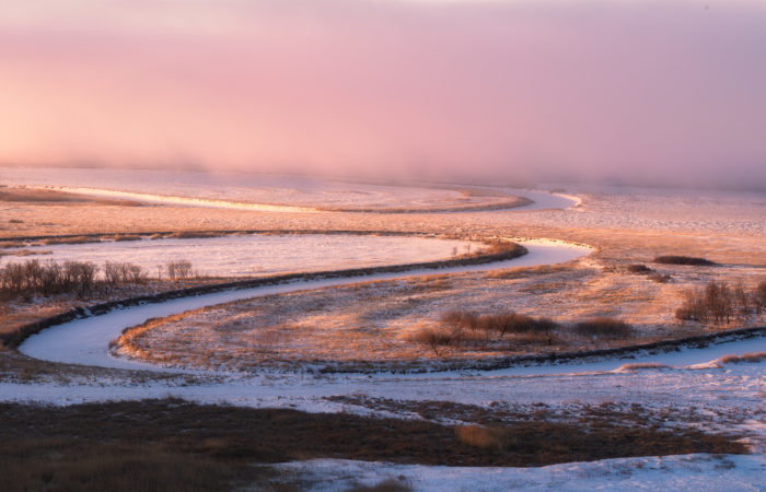 Light hits the Saskatchewan landscape as a frozen river winds through the scene