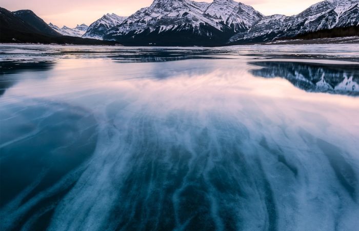 Abraham Lake at sunset. This landscape photograph of the Canadian Rockies includes ice formations that lead the eye to the mountain in the background