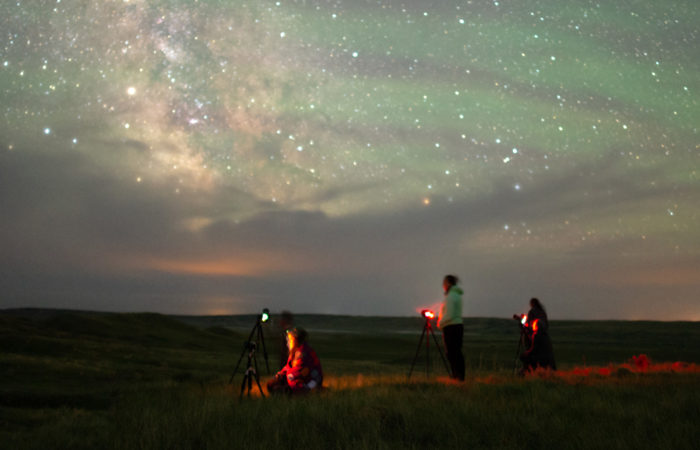 Students participating in a night photography workshop with the milky way in front of them