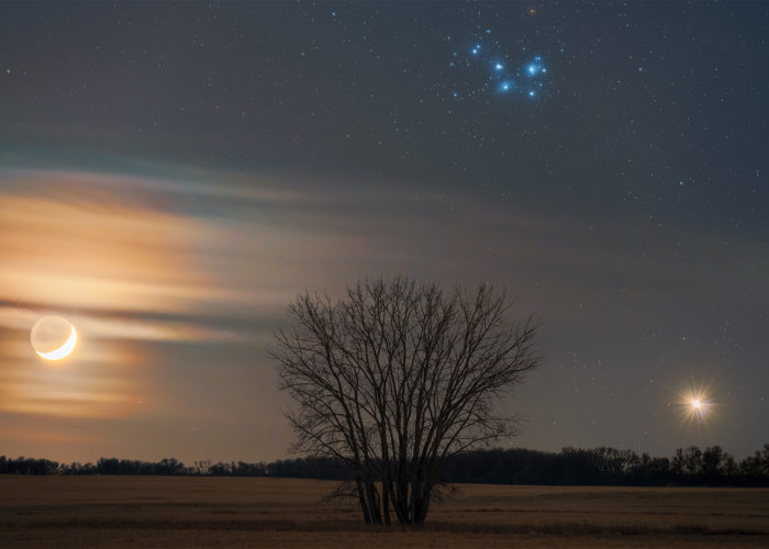 An astrophoto of the conjunction of the moon, Venus, and the Pleiades over the Saskatchewan landscape