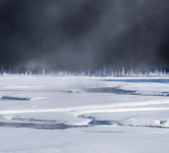 An intimate landscape photograph of the Candian Rockies on a cold winter morning that created steam on the river