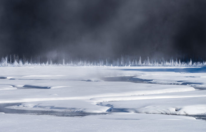 An intimate landscape photograph of the Candian Rockies on a cold winter morning that created steam on the river