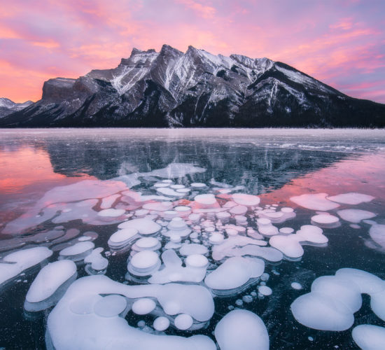 Sunrise photograph of Lake Minnewanka during winter with frozen bubbles