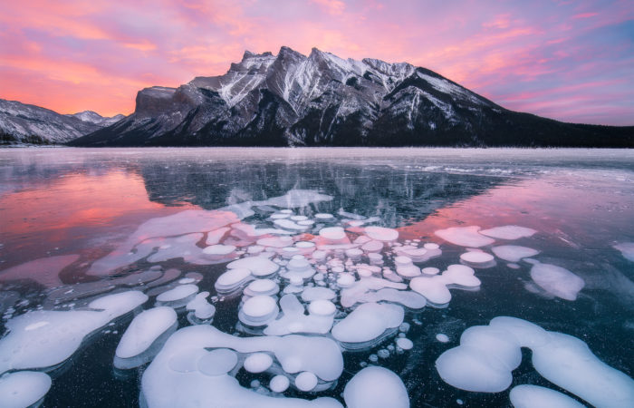 Sunrise photograph of Lake Minnewanka during winter with frozen bubbles