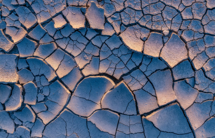 An intimate landscape photograph of sidelit cracked mud at the Massold Clay Canyons in Saskatchewan