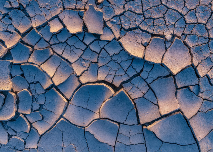 An intimate landscape photograph of sidelit cracked mud at the Massold Clay Canyons in Saskatchewan