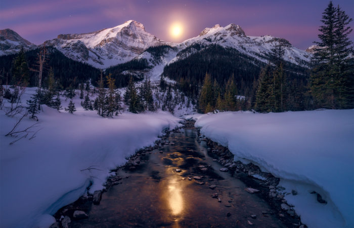 A landscape photograph in the Canadian Rockies of moonset over a Mt Murray