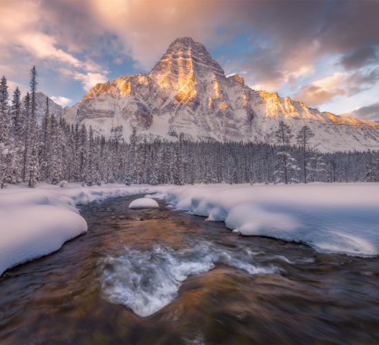 A landscape photograph of Mount Chephren in the Canadian Rockies during a winter sunrise