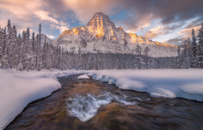 A landscape photograph of Mount Chephren in the Canadian Rockies during a winter sunrise
