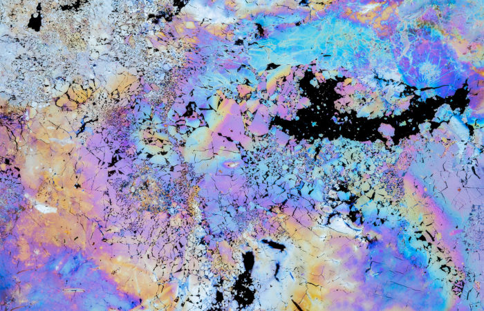 A intimate landscape photograph of the vibrant colours of natural oils in a pool of water