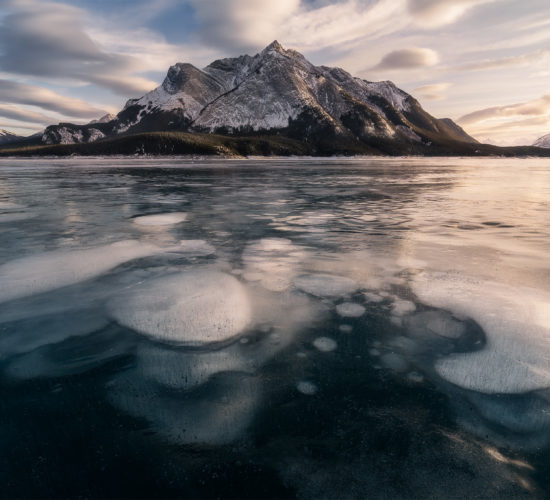 A landscape photograph of Abraham Lake during sunset including the famous ice bubbles in the foreground