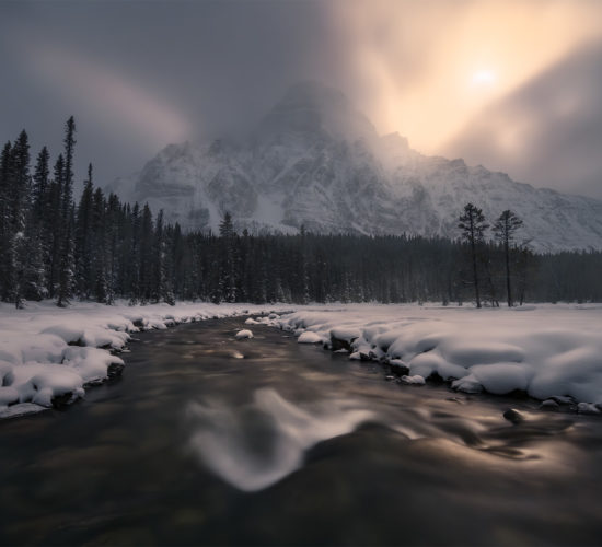 A landscape photograph of the moon setting beside Mount Chephren in Banff National Park