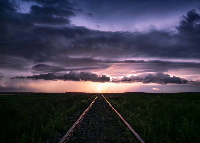 A storm photograph of a lightning strike at the end of a railroad