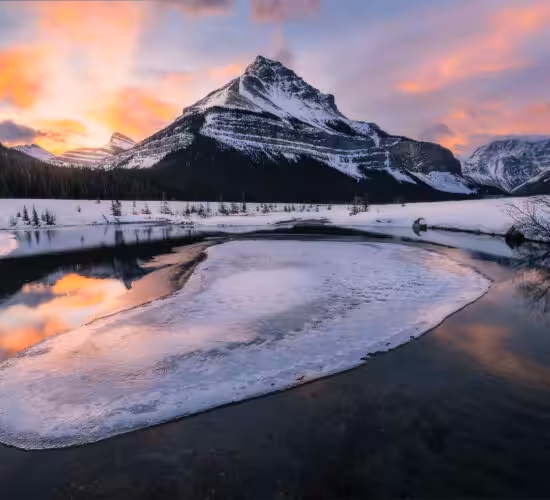 A landscape photograph of the Canadian Rockies in the winter at sunrise