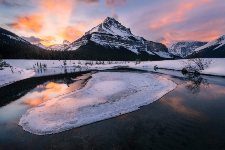 A landscape photograph of the Canadian Rockies in the winter at sunrise