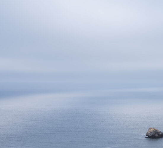 A landscape photograph of light on the ocena with a lone sea stack in the foreground
